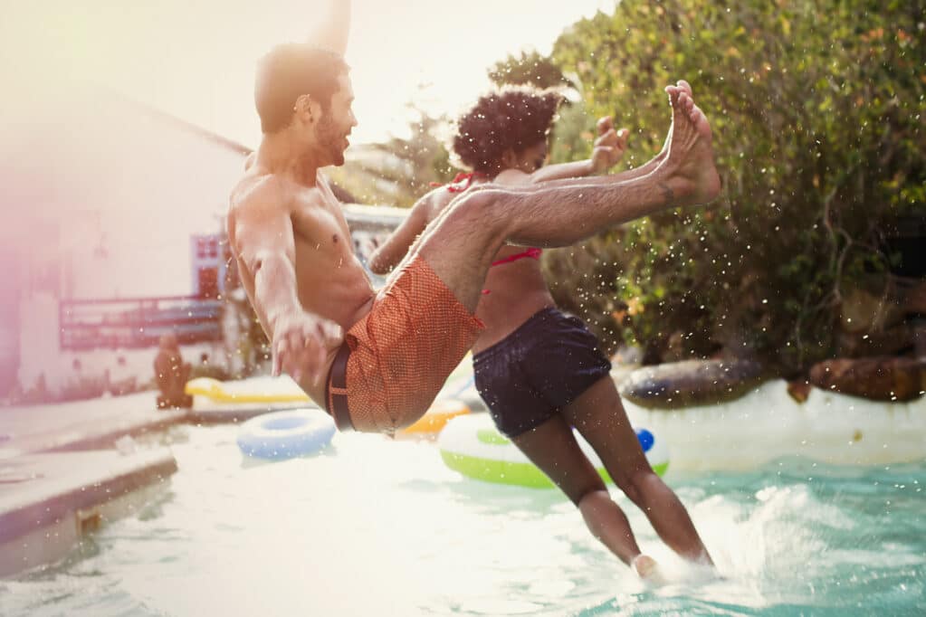 Friends jumping into swimming pool at pool party